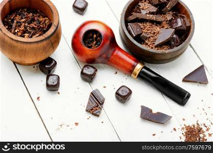 Chocolate flavored tobacco for smoking pipes.Tobacco pipe filled with tobacco.. Smoking pipe with tobacco leaves
