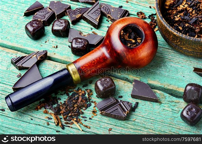 Chocolate flavored tobacco for smoking pipes.Tobacco pipe filled with tobacco.Smoking pipe on wooden table. Chocolate flavored tobacco pipe.