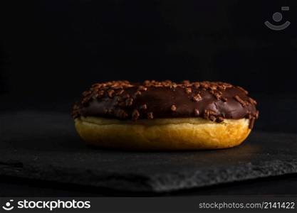 Chocolate glazed donut with chocolate chips isolated. Close up of delicious donut.