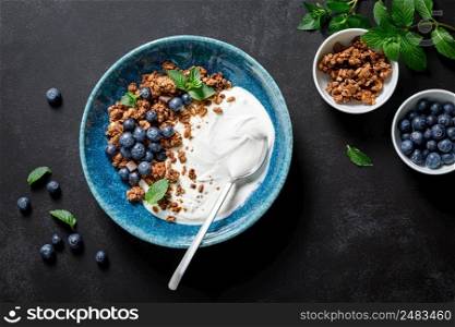 Chocolate granola with white plain yogurt and fresh blueberry in a bowl, healthy food for breakfast, top view