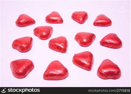 Chocolate heart candies forming a bigger heart shape on a white background