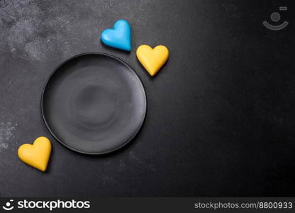 Chocolate hearts in the colors of the Ukrainian flag on a black ceramic plate. Valentine’s day in Ukrainian colors