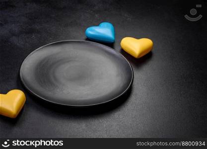 Chocolate hearts in the colors of the Ukrainian flag on a black ceramic plate. Valentine&rsquo;s day in Ukrainian colors