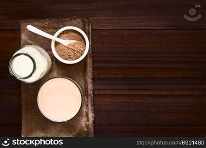 Chocolate milk drink in glass, bottle of milk and chocolate or cocoa powder on the side, photographed overhead with natural light (Selective Focus, Focus on the chocolate drink). Chocolate Milk Drink