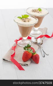 Chocolate mousse and strawberries on wooden table.