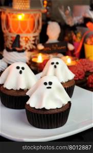Chocolate muffin garnished ghost of marzipan among sweets Halloween