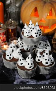 Chocolate muffin with ghost meringues on the table in honor of Halloween