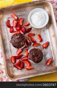 Chocolate muffins with nuts and cherry, metal background, strawberries on side, selective focus