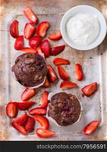 Chocolate muffins with nuts and cherry, metal background, strawberries on side, selective focus