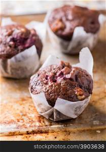 Chocolate muffins with nuts and cherry on metal background, selective focus
