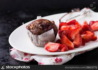 Chocolate muffins with nuts and cherry, strawberries on side, metal background, selective focus