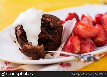 Chocolate muffins with nuts and cherry, strawberries on side, yellow background, selective focus