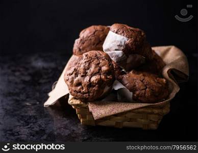 Chocolate muffins with nuts in basket, on dark background, selective focus