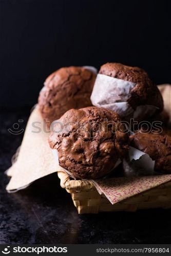 Chocolate muffins with nuts in basket, on dark background, selective focus