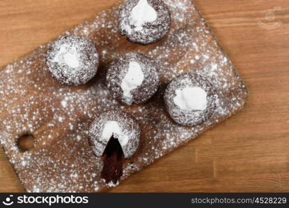 chocolate muffins with white icing lying on a Board sprinkled with powdered sugar