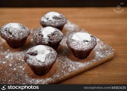 chocolate muffins with white icing lying on a Board sprinkled with powdered sugar
