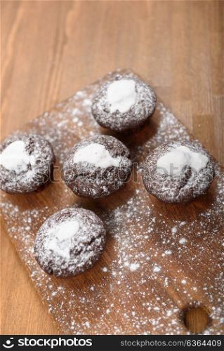 chocolate muffins with white icing lying on a Board sprinkled with powdered sugar