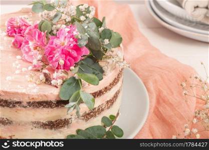 Chocolate naked cake with fresh roses and swiss buttercream on a white background