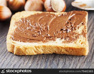 Chocolate over rusk, with hazelnuts on the background, focus on first part of rusk, horizontal image