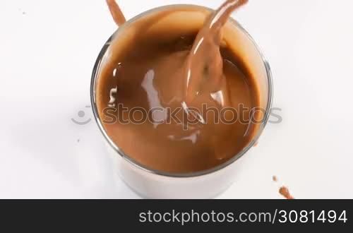 Chocolate pieces falling in milk with chocolate glass in slow motion.