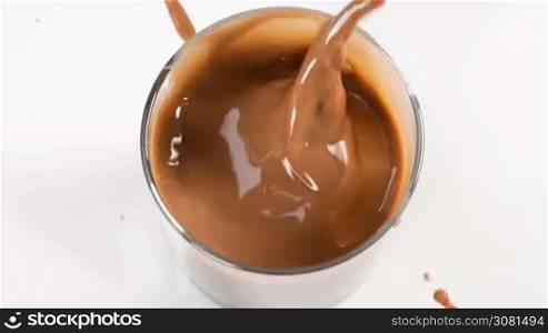Chocolate pieces falling in milk with chocolate glass in slow motion.