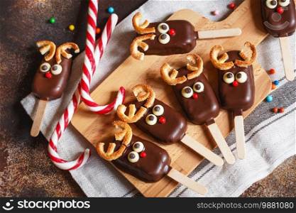 chocolate popsicle. Christmas concept. Chocolate ice cream on a stick with a Christmas deer face with candy red nose 