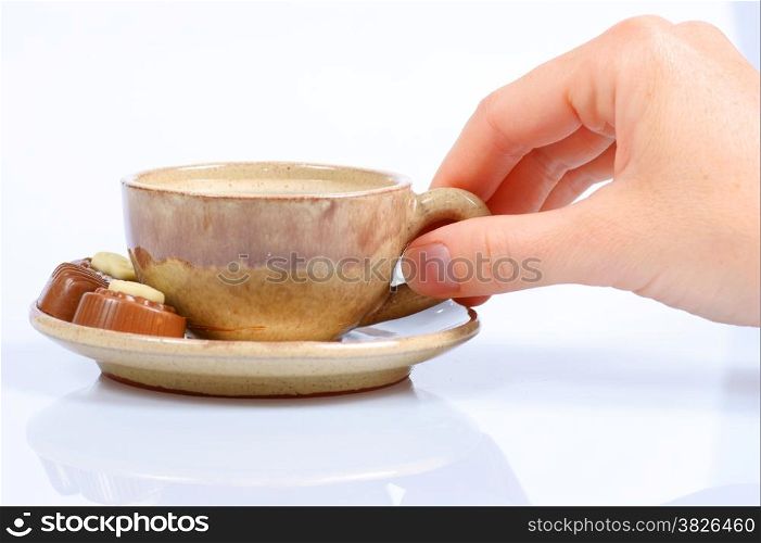 chocolate pralines, cup with black coffee and female hand on white background. Delicious dark and milk chocolate pralines.