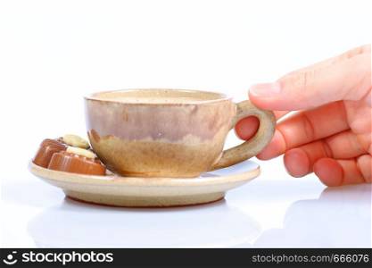 chocolate pralines, cup with black coffee and female hand on white background. Delicious dark and milk chocolate pralines.