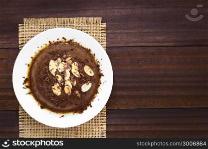 Chocolate pudding or flan dessert with caramel sauce, roasted almond slices and chocolate shavings, photographed overhead with natural light (Selective Focus, Focus on the top of the dessert). Chocolate Pudding or Flan Dessert