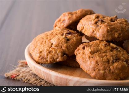 Chocolate raisin cookies arranged on a plate made of wood.