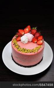 Chocolate strawberry cake decorated with berries, meringue and pistachios