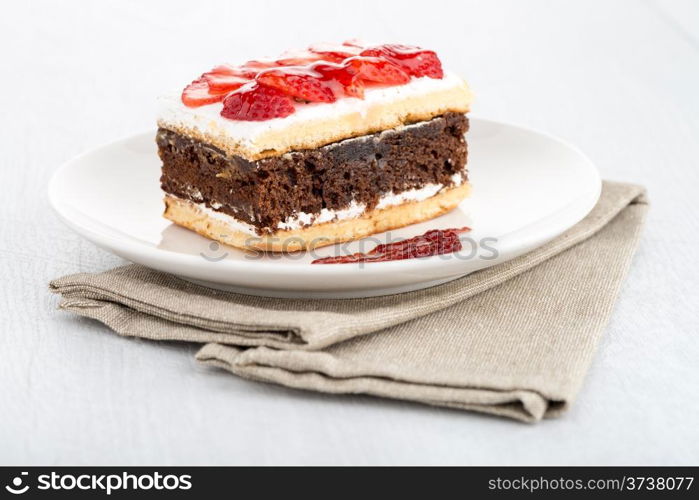 Chocolate strawberry cake on white plate and wooden table.