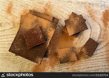 chocolate tablets with pieces on different sizes on bright wood background