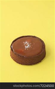 chocolate tartlet with salted caramel on the yellow background