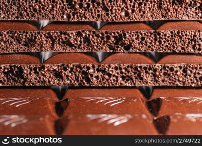 Chocolate. The broken tile of porous black chocolate
