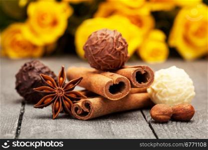 Chocolate truffles and spices over wooden table