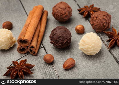 Chocolate truffles and spices over wooden table