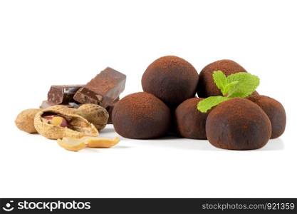 Chocolate truffles, chocolate parts and peanuts with mint leaves isolated on white background.