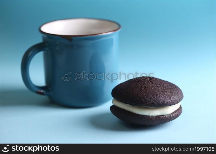 Chocolate Whoopie Pies with Vanilla Buttercream Filling and a cup of tea on a blue background