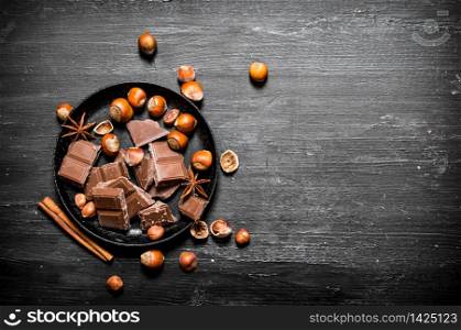 Chocolate with nuts and cinnamon. On the black wooden table.. Chocolate with nuts and cinnamon.