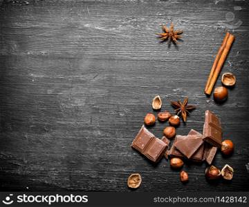 Chocolate with nuts and cinnamon. On the black wooden table.. Chocolate with nuts and cinnamon.