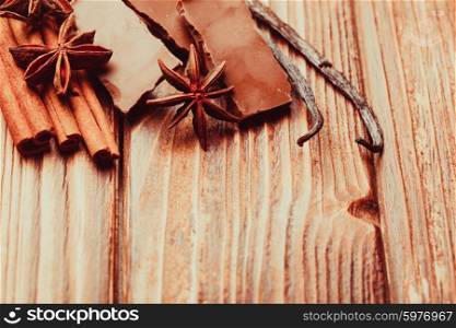 Chocolate with spices - anise, vanilla, cinnamon on the wooden background