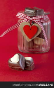 Chocolates in a jar on red background. Valentines day concept