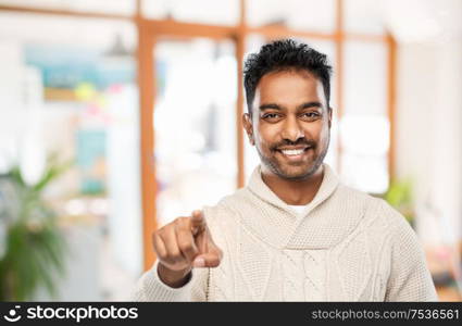 choice, gesture and people concept - smiling indian man pointing finger to camera over office background. smiling indian man pointing finger to camera