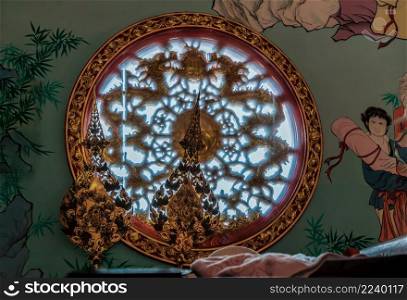 Chonburi, Thailand - 05 Feb 2022 : Chinese-style wall and twin Chinese dragons sculpture decorate on chinese-style circular window through which a ray of light passes. No focus, specifical