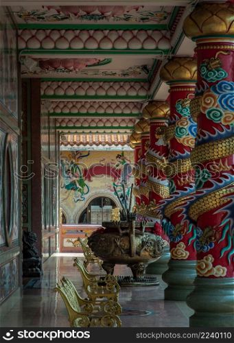 Chonburi, Thailand - 05 Feb 2022 : The magnificent of Chinese-style temple corridor with sculptured dragons pillars, Large incense burner decorated with dragon pattern and has Gold metal benchs for relaxation. Wihan Thep Sathit Phra Ki Ti Chaloem, Selective focus.