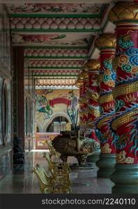 Chonburi, Thailand - 05 Feb 2022 : The magnificent of Chinese-style temple corridor with sculptured dragons pillars, Large incense burner decorated with dragon pattern and has Gold metal benchs for relaxation. Wihan Thep Sathit Phra Ki Ti Chaloem, Selective focus.