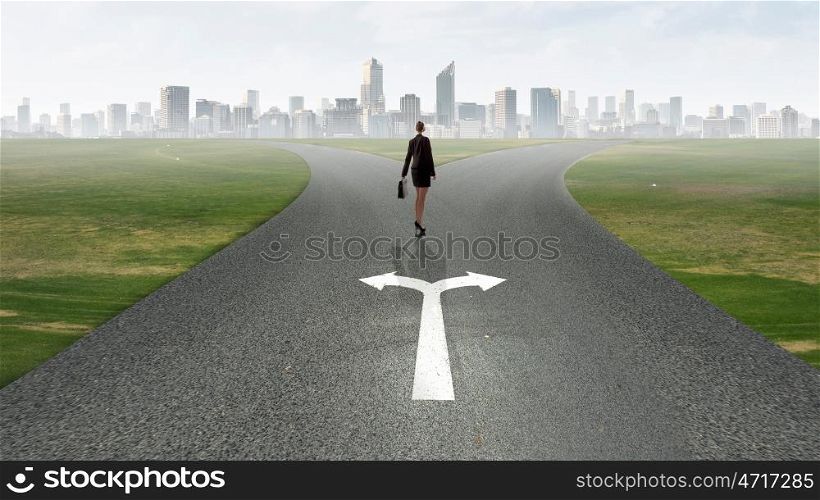 Choose your way. Back view of businesswoman standing on crossroads and making choice