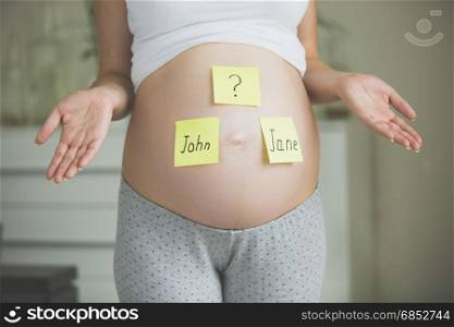 Choosing baby&rsquo;s name. Pregnant woman with names on belly