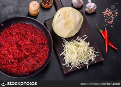 Chopped beetroot in a pan as well as spices and herbs on a wooden cutting board as ingredients in the preparation of traditional Ukrainian borscht. Chopped beetroot in a pan as well as spices and herbs on a wooden cutting board